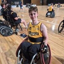 A teenager in a wheelchair sits on a wheelchair rugby court